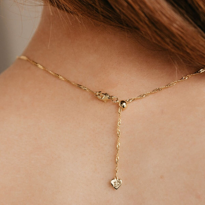 The extra chain hanging down the back, ending in a small heart