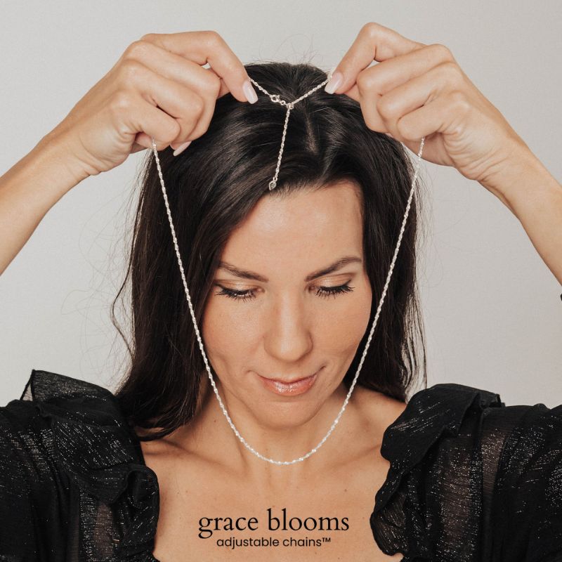 A woman slipping a Grace Blooms adjustable chain over her head with the clasp still closed